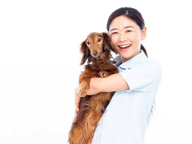 犬を抱きかかえて笑う女性